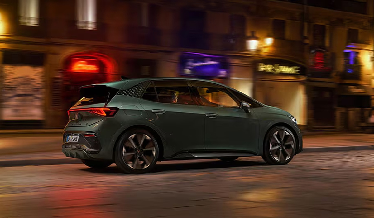 CUPRA Born VZ in Seitenansicht bei Nacht mit farbigen Lichteffekten im Hintergrund